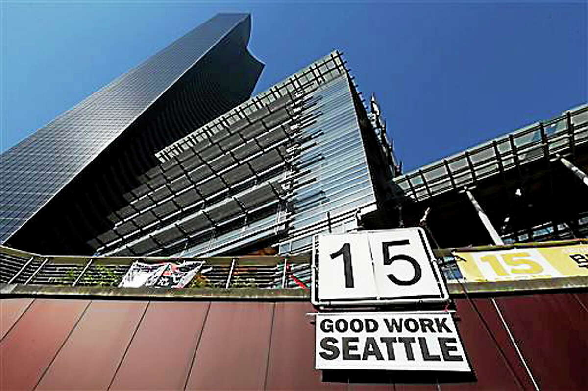 A sign that reads "15 Good Work Seattle" is displayed below Seattle City Hall, right, and the Columbia Center building, left, Monday, June 2, 2014, after the Seattle City Council passed a $15 minimum wage measure. (AP Photo/Ted S. Warren)