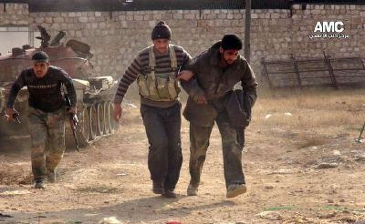 In this Monday, Nov. 11, 2013 file photo, citizen journalism image provided by Aleppo Media Center AMC, which has been authenticated based on its contents and other AP reporting, two Free Syrian Army fighters help a wounded comrade during clashes in Aleppo, Syria.