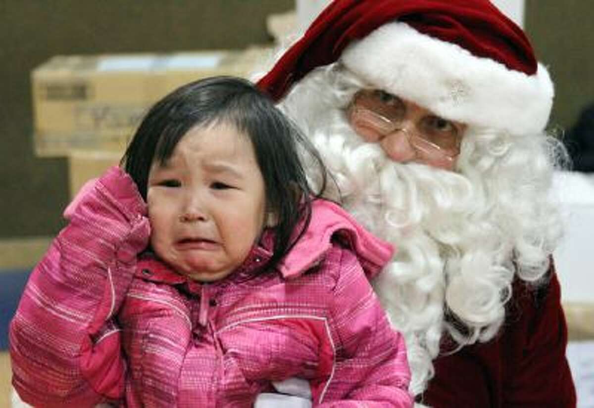 This photo taken Dec. 11, 2013, in Kwethluk, Alaska, shows Alaina David, 2, crying while having her photo taken with Santa.