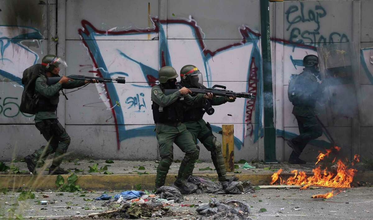 Bolivarian National Guard fire tear gas at anti-government protesters marching to the Supreme Court opposing President Nicolas Maduro's plan to rewrite the constitution, in Caracas, Venezuela, Saturday, July 22, 2017. Venezuelan authorities have routinely responded with tear gas and rubber bullets to nearly four months of street protests, during which at least 97 people have died in the unrest and thousands more have been injured or detained. (AP Photo/Fernando Llano)