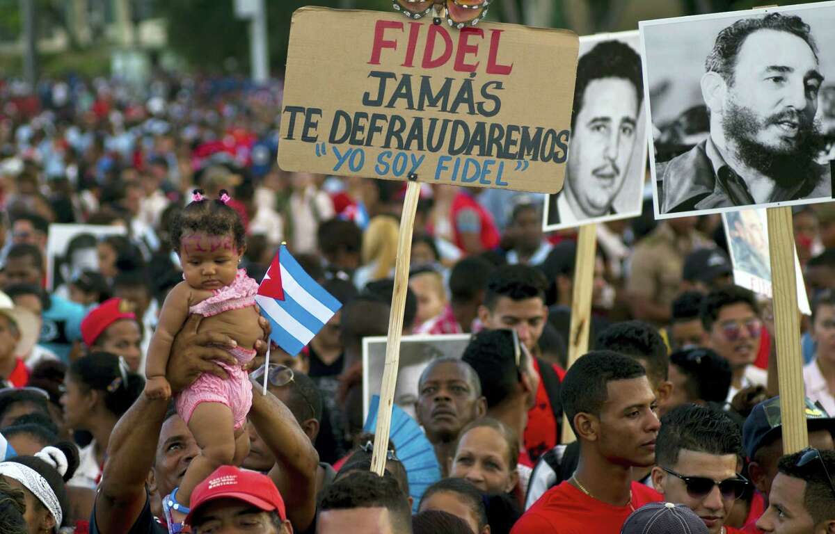 People waits for the beginning of a rally honoring Cuba's leader Fidel Castro before his burial Sunday at the Plaza Antonio Maceo in Santiago, Cuba, Saturday, Dec. 3, 2016. The sign reads in Spanish 'Fidel we will never let you down. I am Fidel.'(AP Photo/Ramon Espinosa)