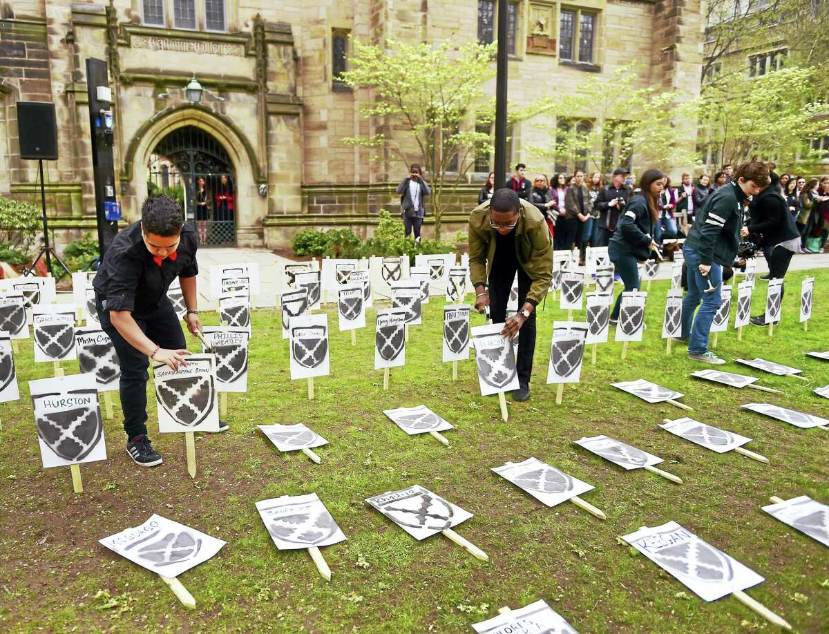 (Peter Hvizdak - New Haven Register) Yale University undergraduate Nicholas Aromoyo, left, an organizer of a renaming ceremony Friday, April 29, 2016 for Calhoun College at Yale, with others, hammers down a plaque at Yale's Cross Campus in front of Calhoun College with a suggested name during a demonstration that protested the Yale administrations refusal to change the college's name. John Calhoun, a vice president and U.S. senator, was an avowed white supremacist and slaveholder.