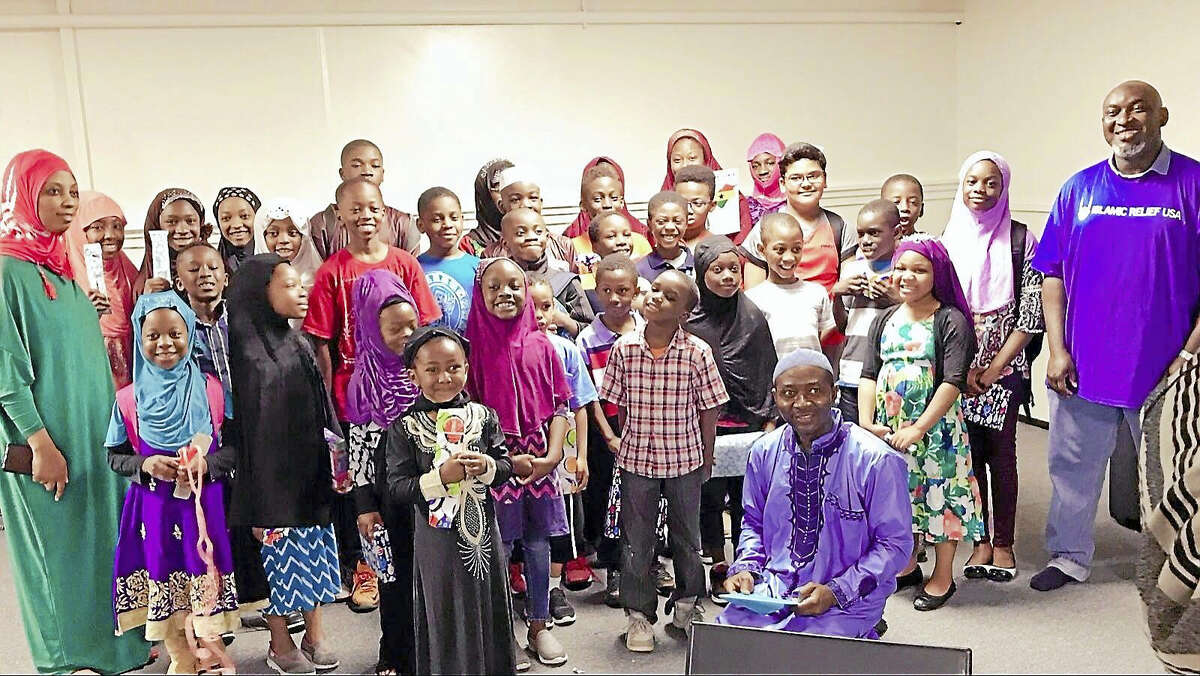 Contributed photo The children of BAQIS Fellowship, Inc. pose with their toys. Their teacher, BAQIS President Mohamed Turay is sitting. Far right is Islamic Relief USA volunteer and MHSI board member who delivered the toys.
