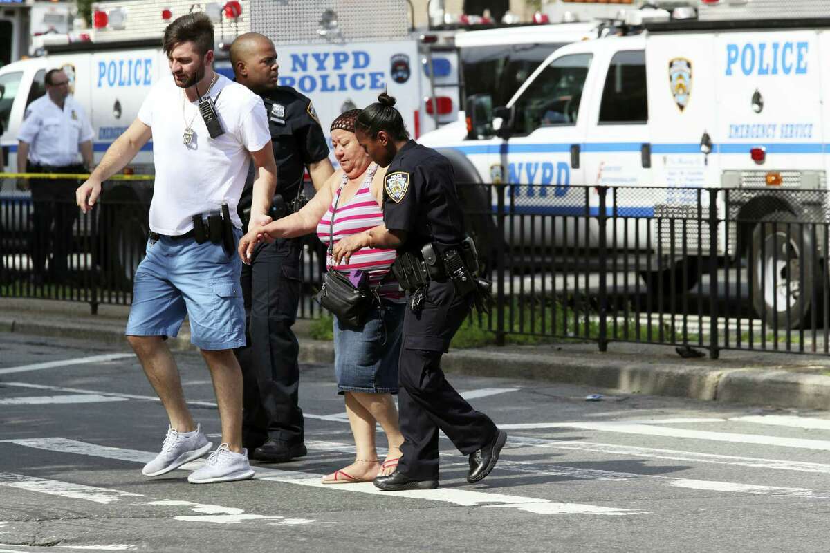 Police help people cross the street outside the Bronx Lebanon Hospital in New York after a gunman opened fire there on Friday, June 30, 2017. The gunman, identified as Dr. Henry Bello who used to work at the hospital, returned with a rifle hidden under his white lab coat, law enforcement officials said.