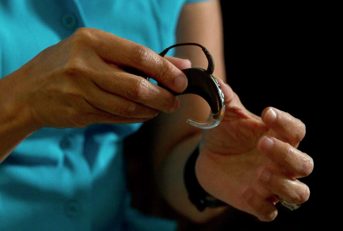 Susan Langlois shows her cochlear implant, a surgically implanted medical device that sends sounds signals to the brain, during an interview at her home Wednesday, July 5, 2017, in Spring.