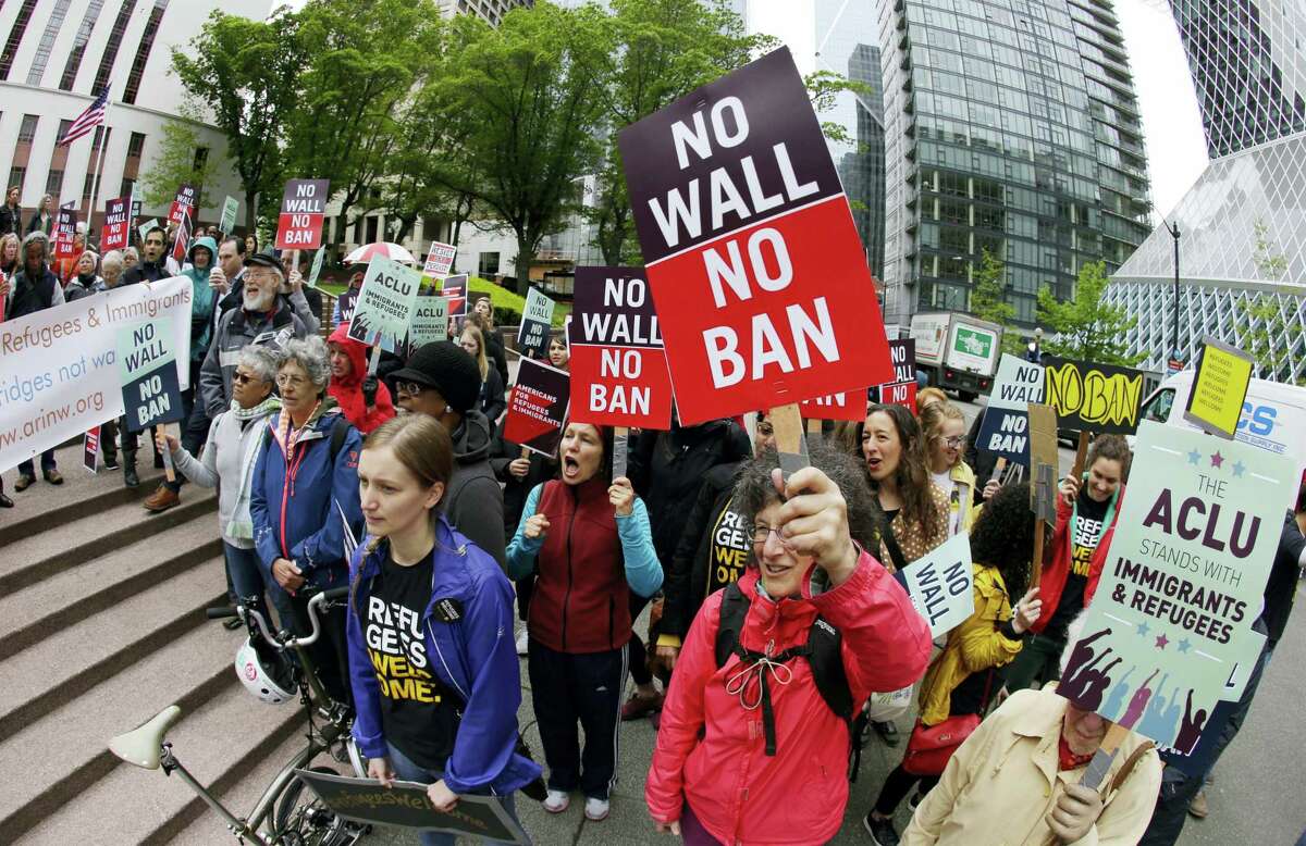 In this May 15, 2017 photo, protesters wave signs and chant during a demonstration against President Donald Trump’s revised travel ban, outside a federal courthouse in Seattle. The Supreme Court is letting the Trump administration enforce its 90-day ban on travelers from six mostly Muslim countries, overturning lower court orders that blocked it.
