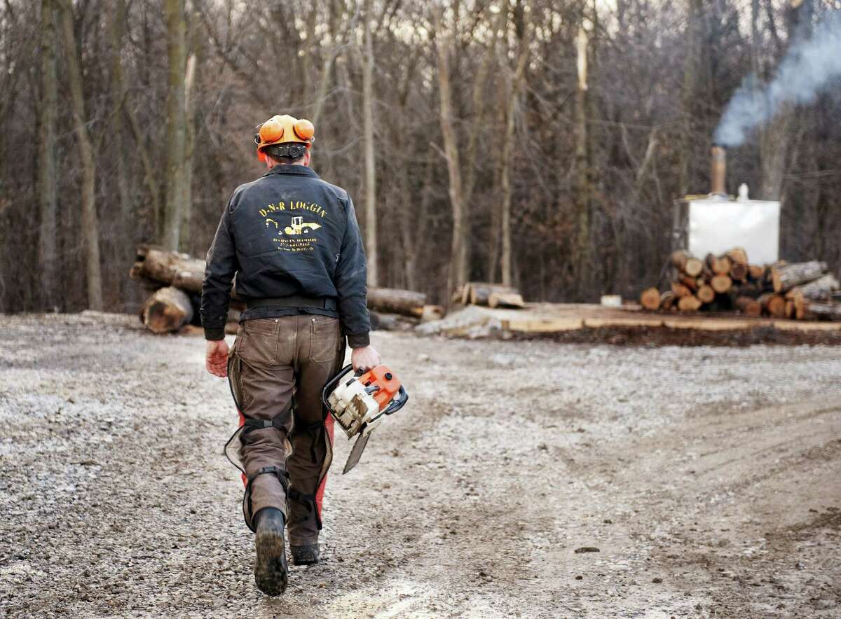 Darwin Woods carries a chainsaw to cut wood for the wood burning stove he uses to heat both water and his home in Clark, Mo.