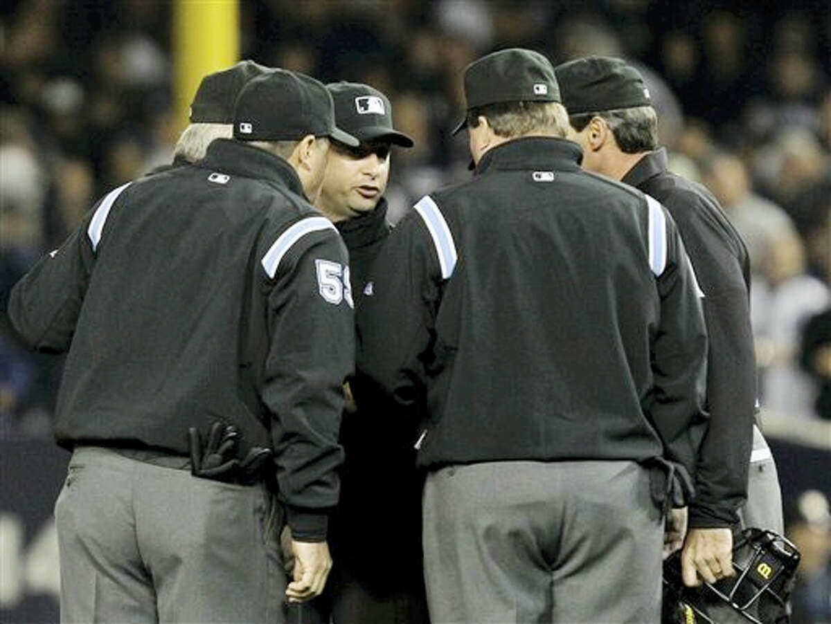 This Oct. 19, 2010 photo shows umpires huddling after an apparent home run by New York Yankees’ Lance Berkman in the second inning of Game 4 of baseball’s American League Championship Series against the Texas Rangers in New York. Major League Baseball umpires could start explaining replay decisions to the players and fans — the way NFL referees do — later this season if the sides can reach agreement. Under one possible scenario, the crew chief could wear a microphone beginning at the All-Star Game.