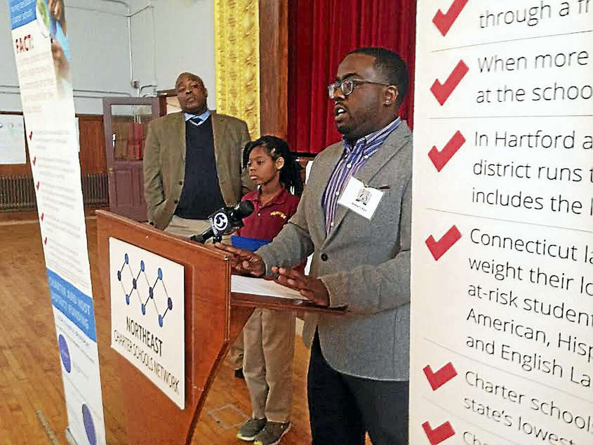 Jeremiah Grace, Connecticut state director for the Northeast Charter Schools Network, speaks at a press event Tuesday. He is joined by Booker T. Washington Academy Executive Director John Taylor and third-grade student Zahariyana Jenkins.
