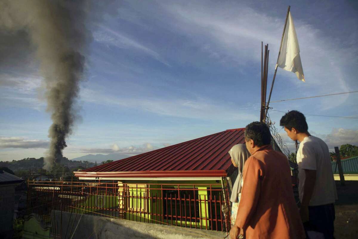 A resident looks at a burning structure during early morning airstrikes by government forces in the continuing fight for Marawi city by Muslim militants Friday, June 23, 2017, in southern Philippines. The siege by militants aligned with the Islamic State group continues as it enters its second month Friday.