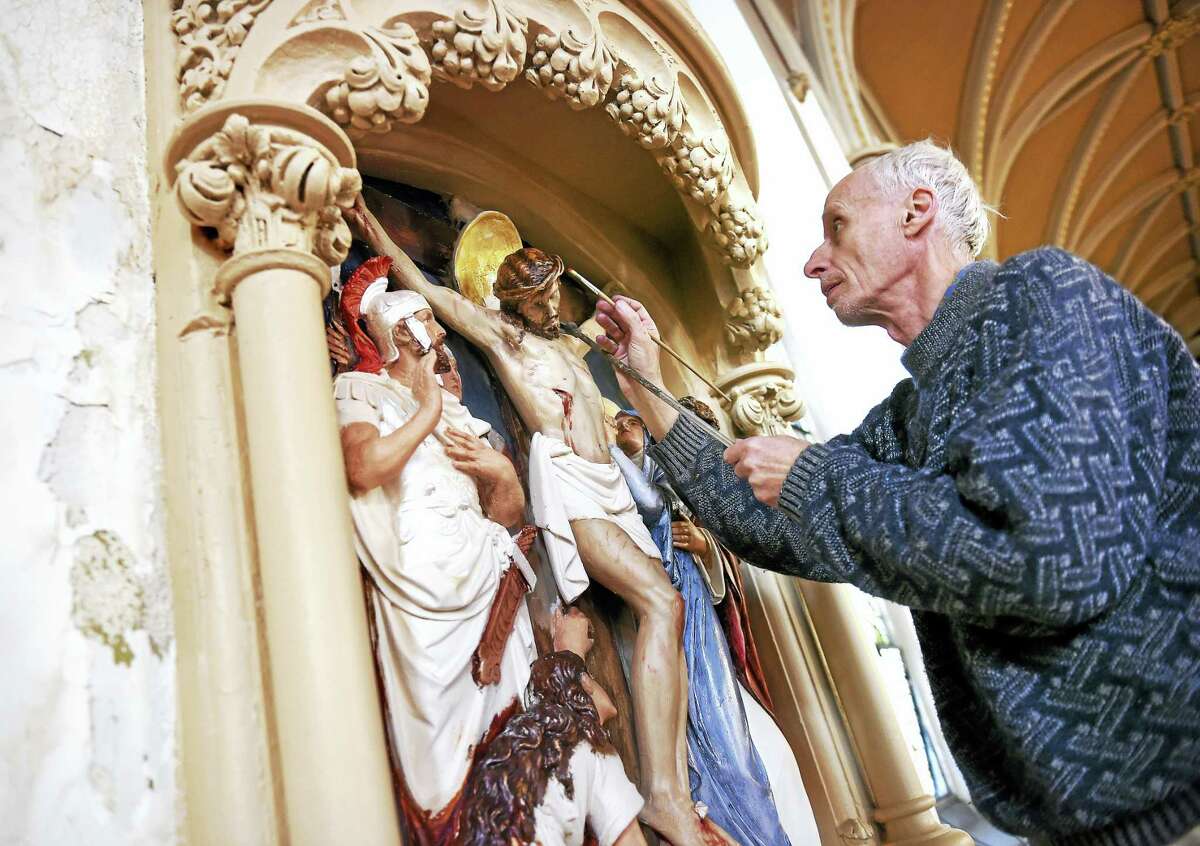 Henry Pospieszalski paints near the crown of Jesus on the 12th Station of the Cross at the Church.
