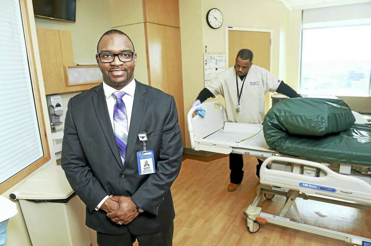 George Pressley, left, System Director for ABM Healthcare Support Services, is photographed in a room in the Smilow Cancer Hospital with Anthony Harris cleaning a bed.
