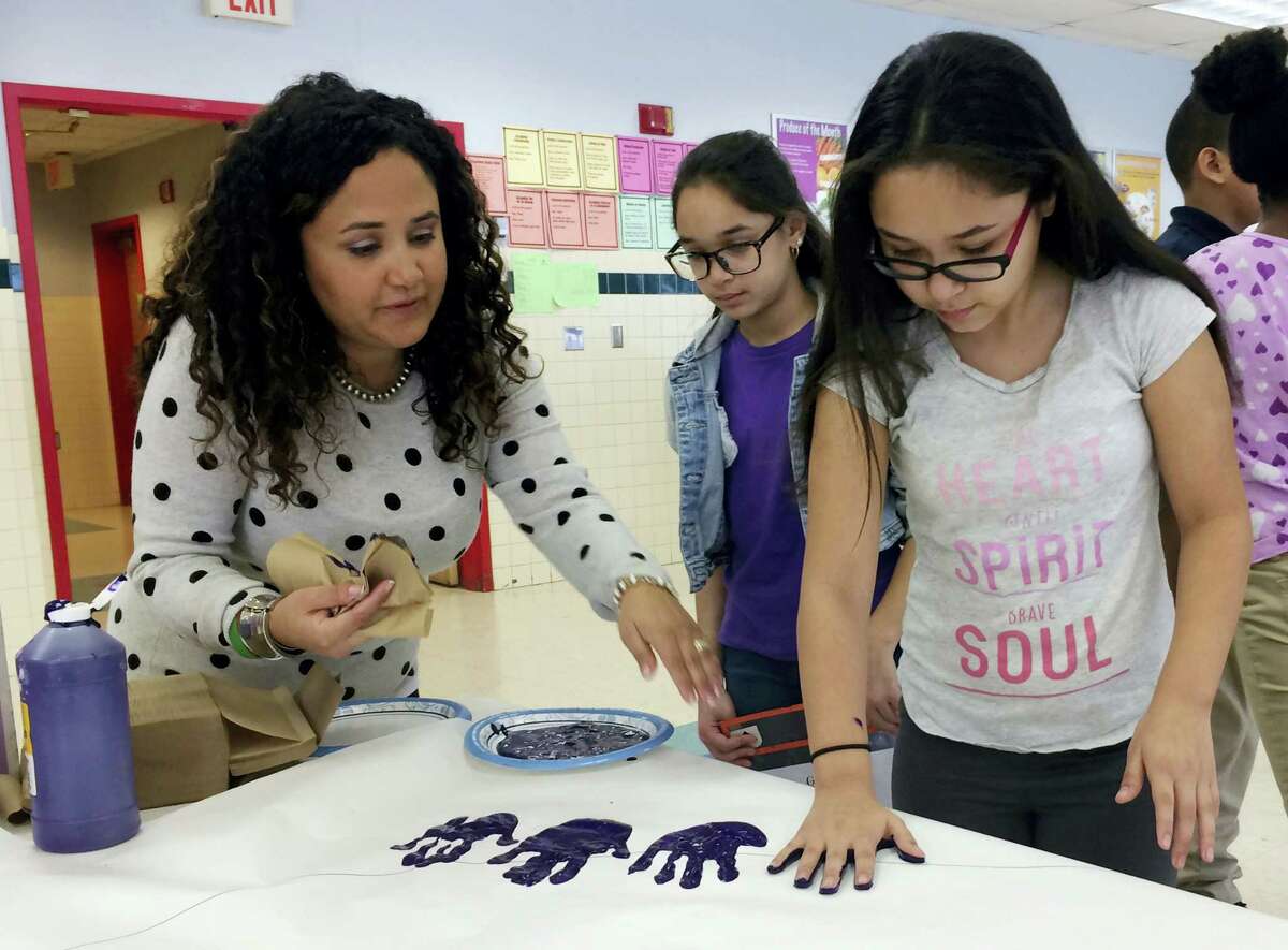In this Feb. 14, 2017 photo, Nelba Marquez-Greene helps 10-year-old Araceli Buchko put her hand print inside a giant paper heart as part of the Love Win’s campaign’s Friendship Day, a social and emotional learning activity at the Chamberlain Elementary School in New Britain, Conn.