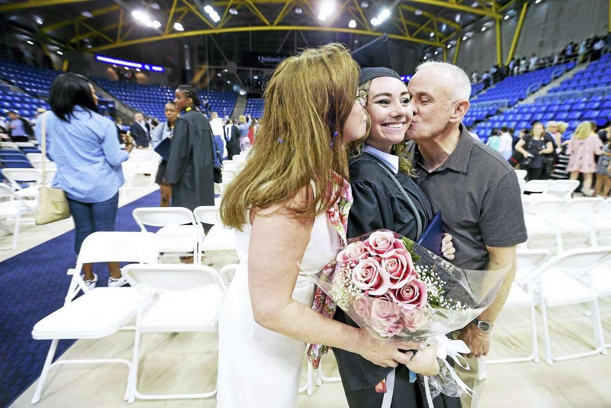 Annemarie Pistilli (left) of Staten Island and her husband, Jonathan (right), kiss their daughter, Rebecca, after commencement exercises for Quinnipiac University’s College of Arts and Sciences at the TD Bank Sports Center in Hamden on 5/20/2017.