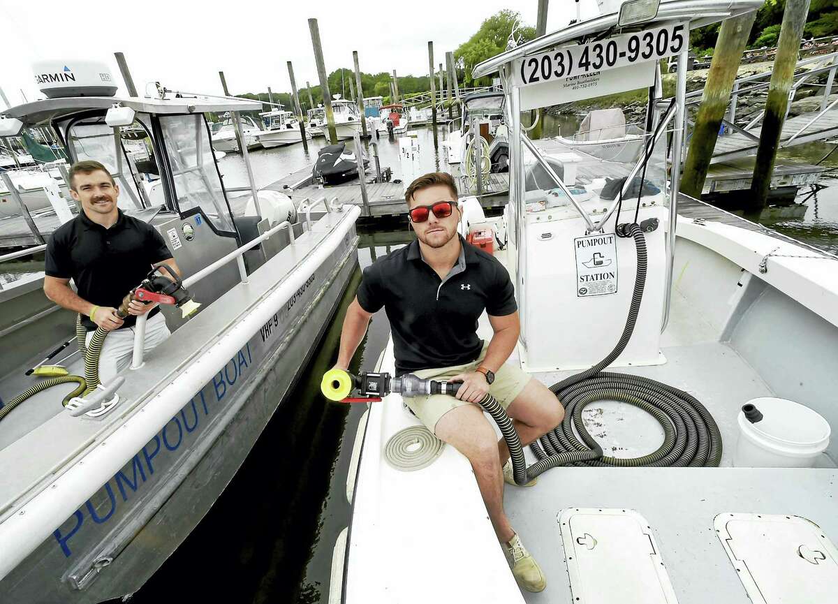 Alex Altermatt, operation director of the Coastal Tide Marine Service, left, and Jay Meriano, executive director of Coastal Tide Marine Service on boats that are designed to pump out waste from boats at the Bruce and Johnson Marina in Branford. The boat at right will be replaced with a new solar-powered pump-out boat.