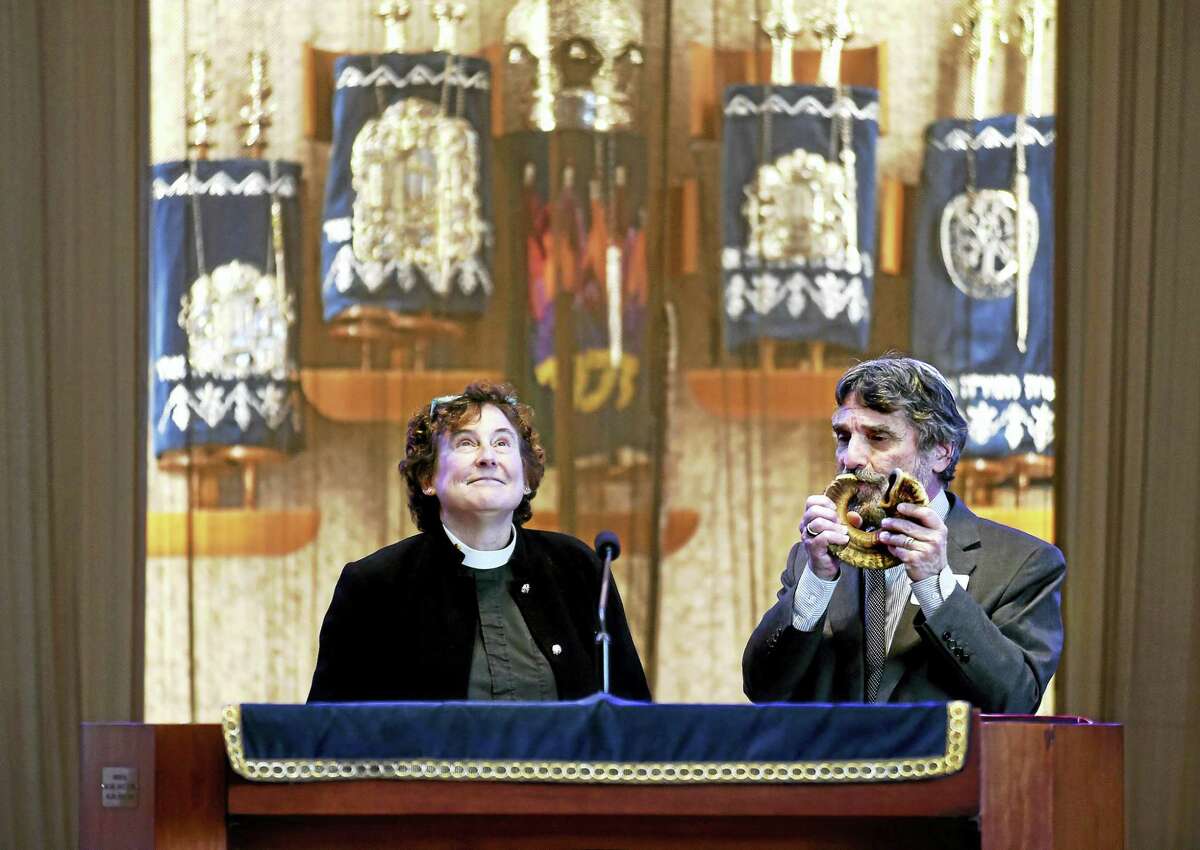 Rev. Daphne Burt, left, recites the Jericho Prayer while Rabbi Herbert Brockman blows the shofar at a meeting about sanctuary congregations.