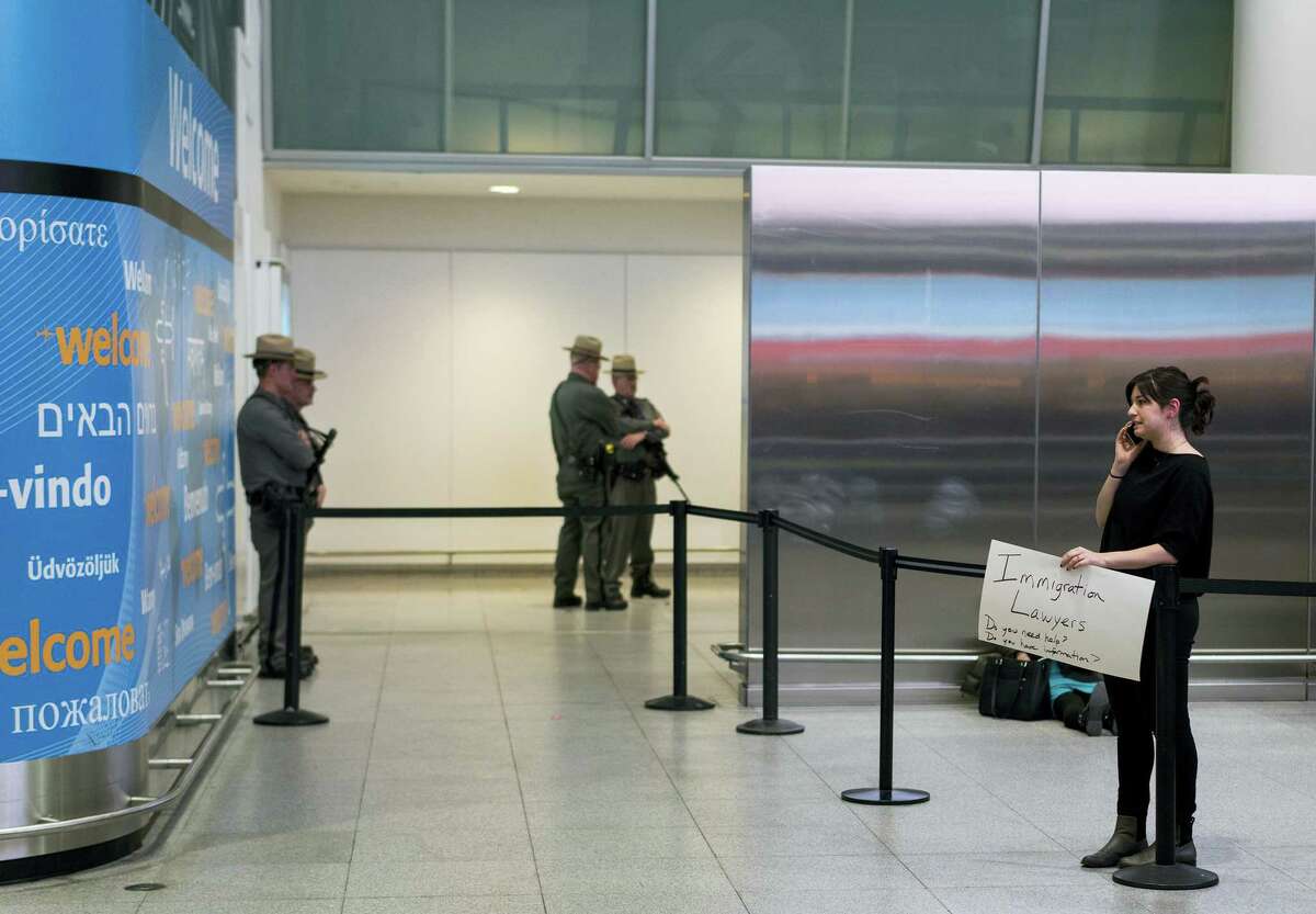 Person holds a sign near an passenger exit point inside Terminal 4 at John F. Kennedy International Airport in New York on Saturday after earlier in the day two Iraqi refugees were detained while trying to enter the country.