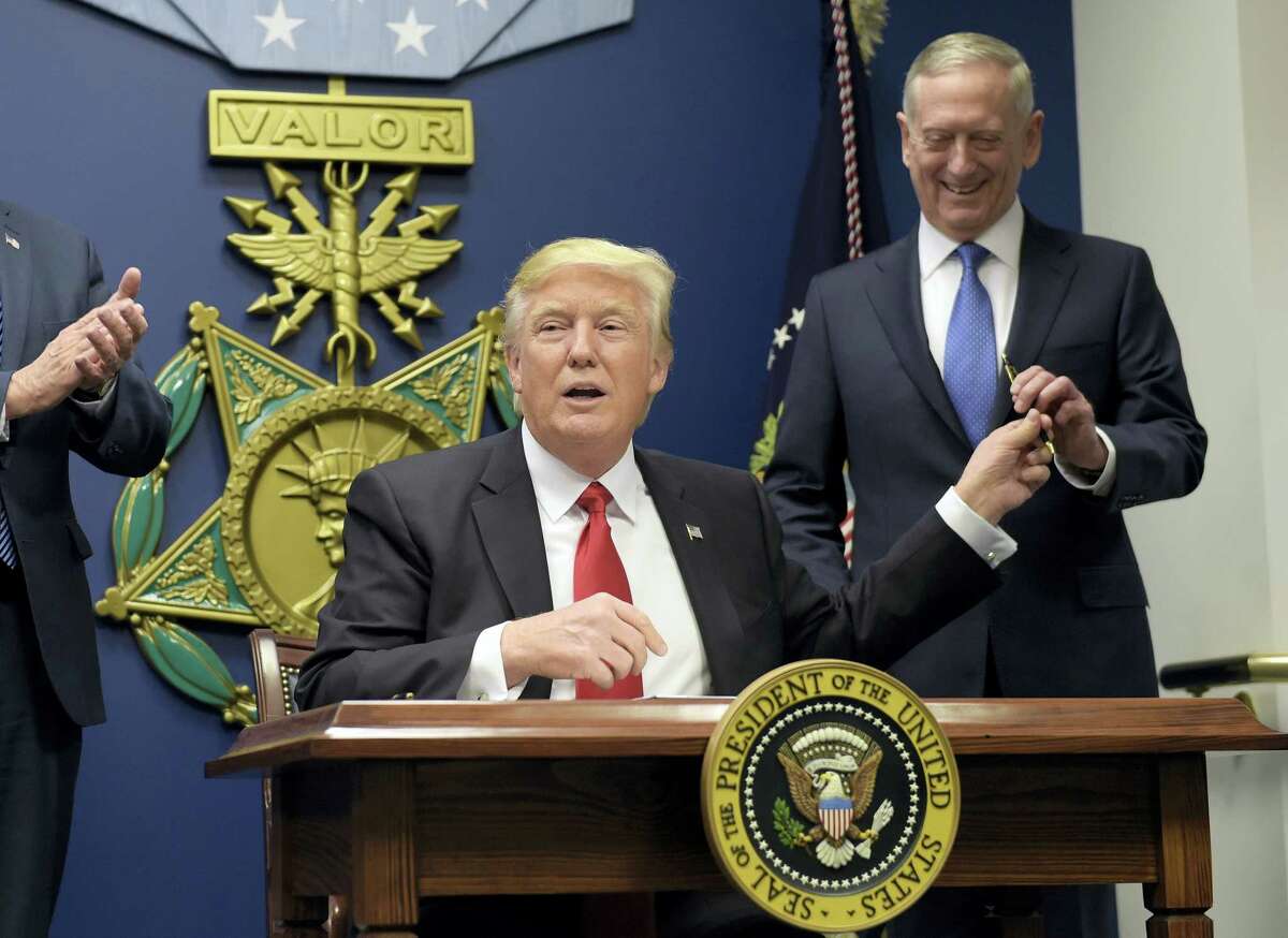 President Donald Trump, left, hands Defense Secretary James Mattis, right, a pen after he signed an executive action on rebuilding the military during an event at the Pentagon in Washington Friday.