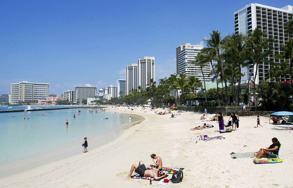 In this March 13 photo, people relax on the beach in Waikiki in Honolulu. Many Americans might dream of going on vacation to places such as Waikiki, but a new poll shows nearly half of Americans won’t be taking a summer vacation this year, mostly because they can’t afford it and some because they can’t get away from work.