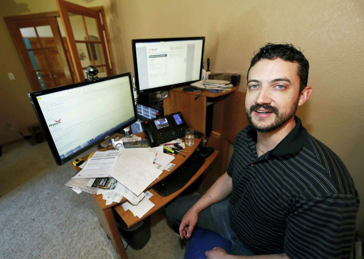 Danny Aguilar poses from his office in his home in Lakewood, Colo. Aguilar, like nearly half of Americans surveyed in a new poll conducted by The Associated Press-NORC Center Public Affairs Research, said they will not be taking a vacation this summer because they can not afford it or can not get time away from the job.