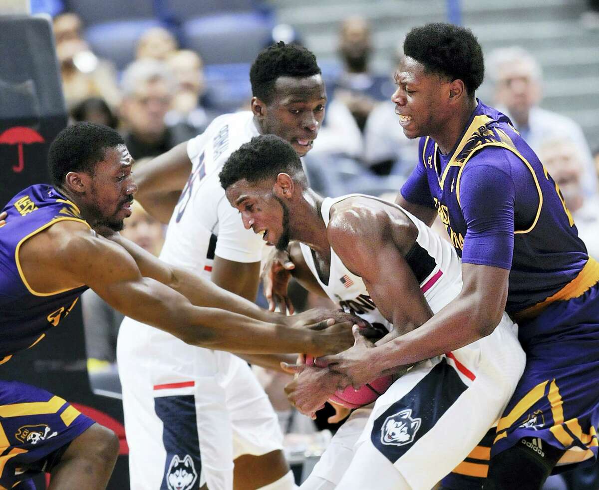 UConn’s Kentan Facey (12) hangs on to a rebound against East Carolina defenders in the second half of Sunday’s 72-65 win for the Huskies over East Carolina.