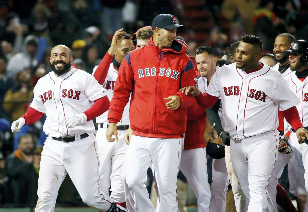 Boston Red Sox’s Sandy Leon, left, celebrates with teammates including Rick Porcello, center, and Pablo Sandoval, right, after hitting a three-run home run during the 12th inning of a baseball game against the Pittsburgh Pirates in Boston, Wednesday. The Red Sox won 3-0.