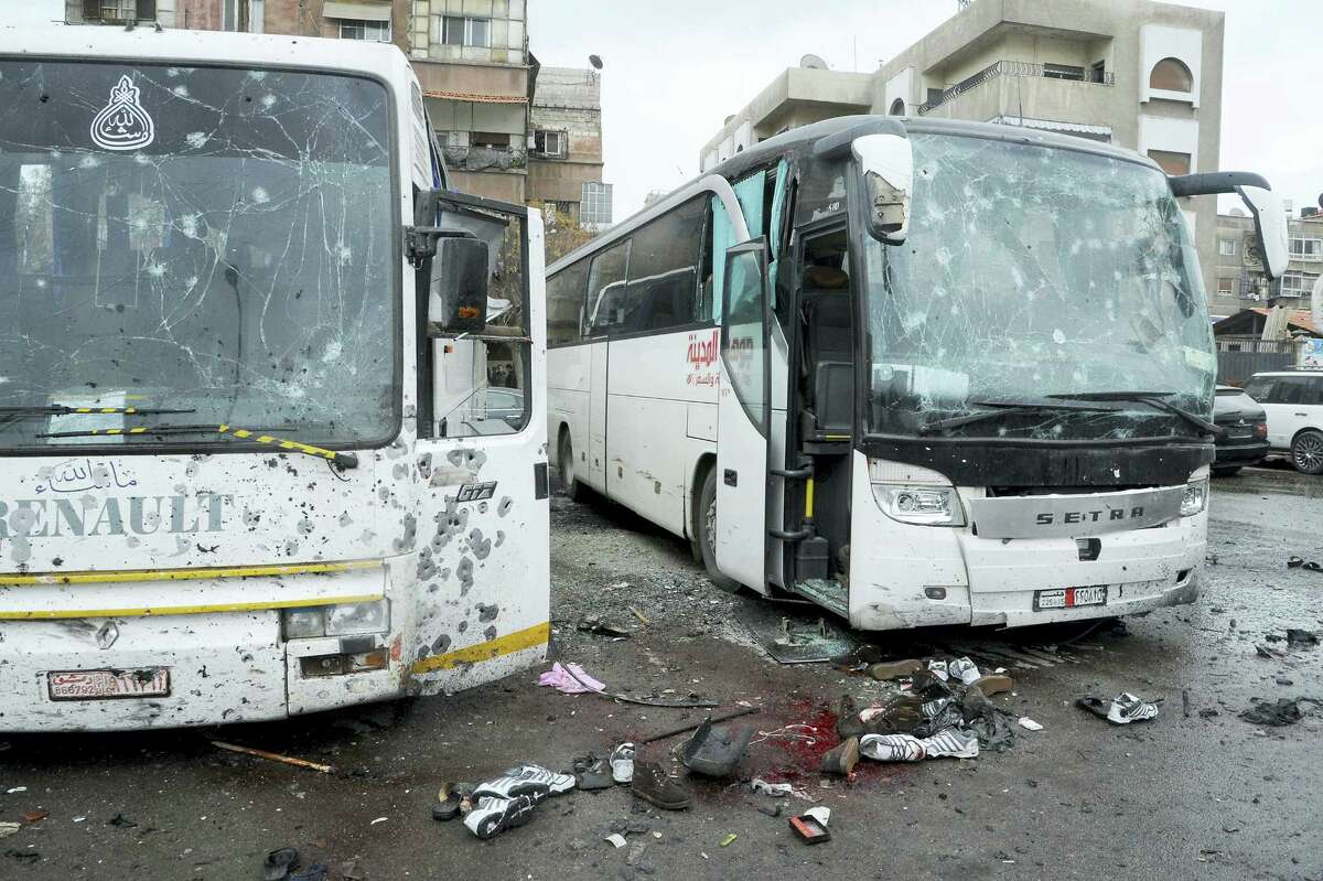 In this photo released by the Syrian official news agency SANA shows blood soaked streets and several damaged buses in a parking lot at the site of an attack by twin explosions in Damascus, Syria, Saturday, March 11, 2017. Twin explosions Saturday near religious shrines frequented by Shiite pilgrims in the Syrian capital Damascus killed dozens of people, Arab media and activists report.