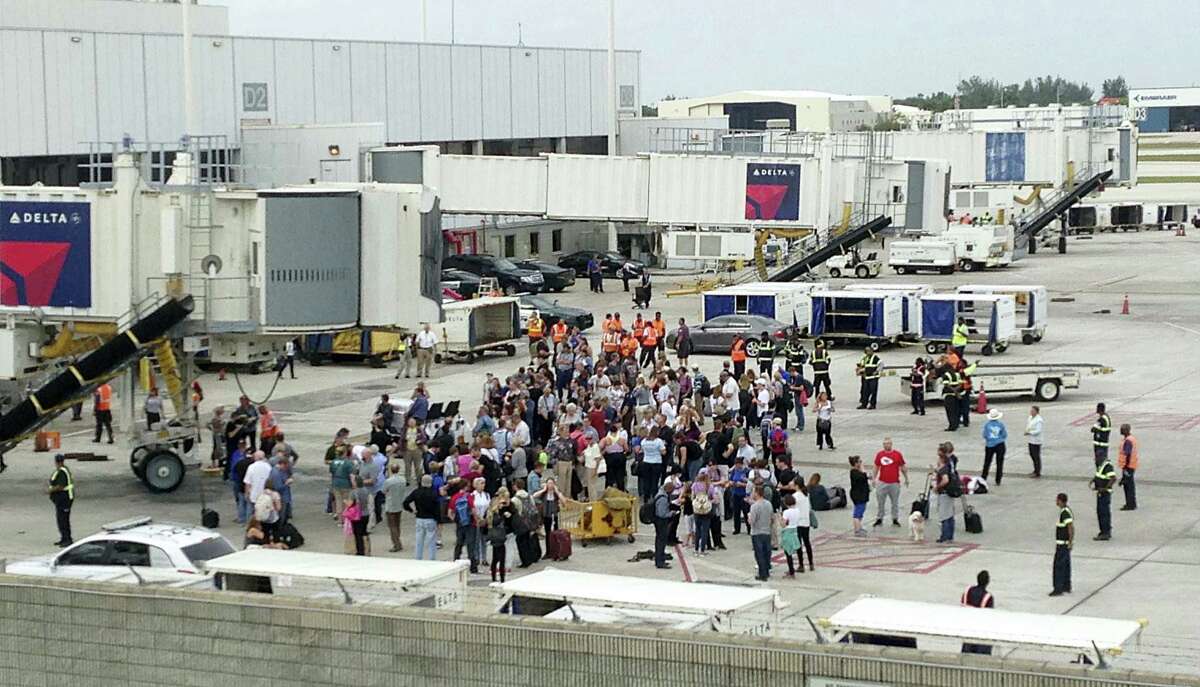 People stand on the tarmac at the Fort Lauderdale-Hollywood International Airport after a shooter opened fire inside a terminal of the airport, killing at least five people and wounding others before being taken into custody, Friday, Jan. 6, 2017, in Fort Lauderdale, Fla.