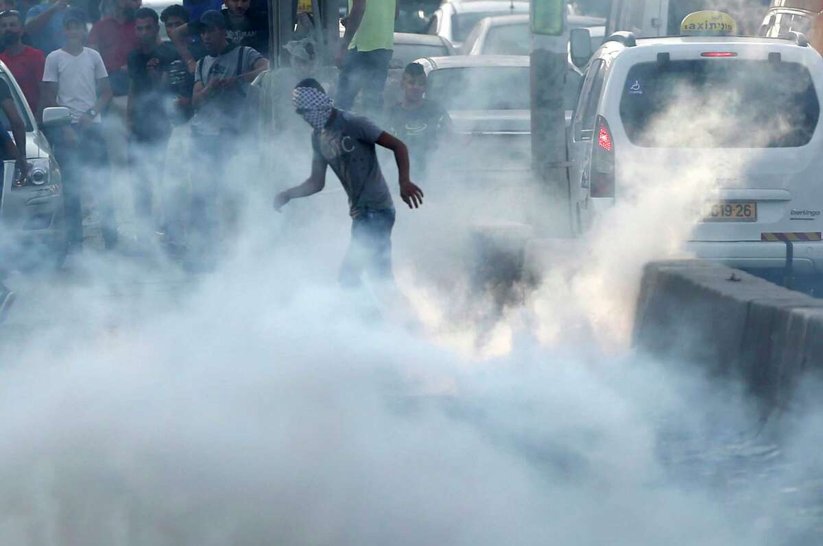 A Palestinian protester stands in tear gas during clashes near the Qalandia checkpoint between Jerusalem and the West Bank city of Ramallah, Sunday, July 23, 2017. Israel's minister of public security said Sunday taht metal detectors set at the entrance to a major Jerusalem shrine that angered Palestinians could be removed if police have another way of ensuring security there. (AP Photo/Nasser Shiyoukhi)