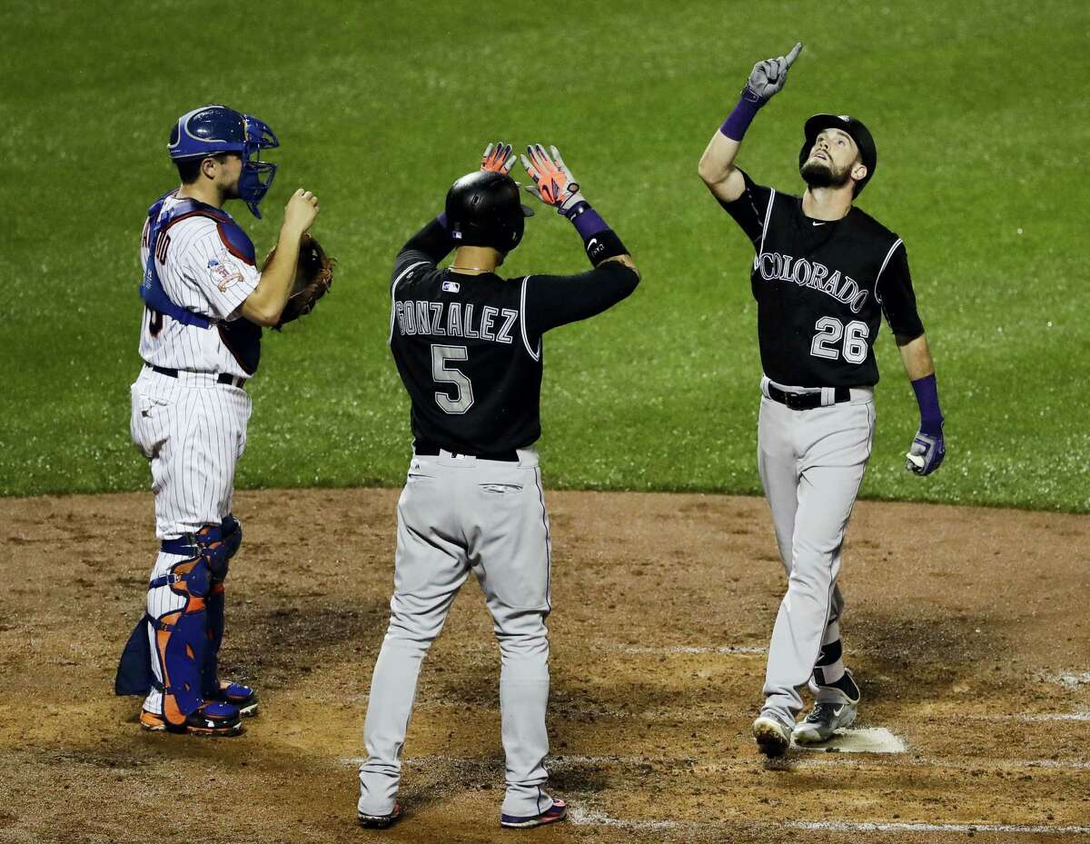 Colorado Rockies’ David Dahl (26) and Carlos Gonzalez (5) celebrate after Dahl hit a two-run home run during the fourth inning of a baseball game as New York Mets catcher Travis d’Arnaud, left, watches, Saturday, July 30, 2016, in New York. (AP Photo/Frank Franklin II)