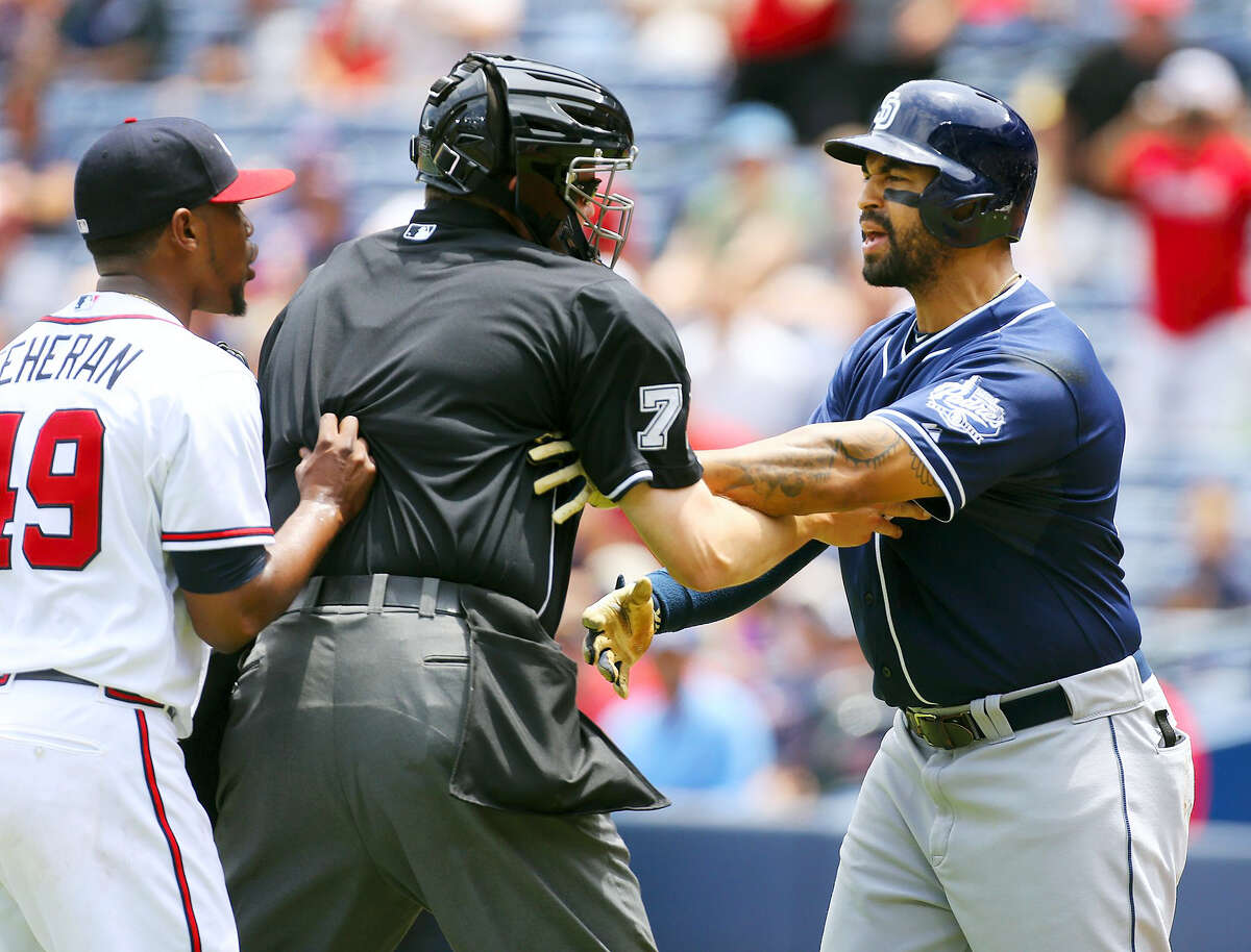 Home plate umpire Jordan Baker separates Atlanta Braves pitcher Julio Teheran, left, and San Diego Padres’ Matt Kemp after Teheran hit Kemp with a pitch during the first inning in a baseball game on June 11, 2015 in Atlanta.