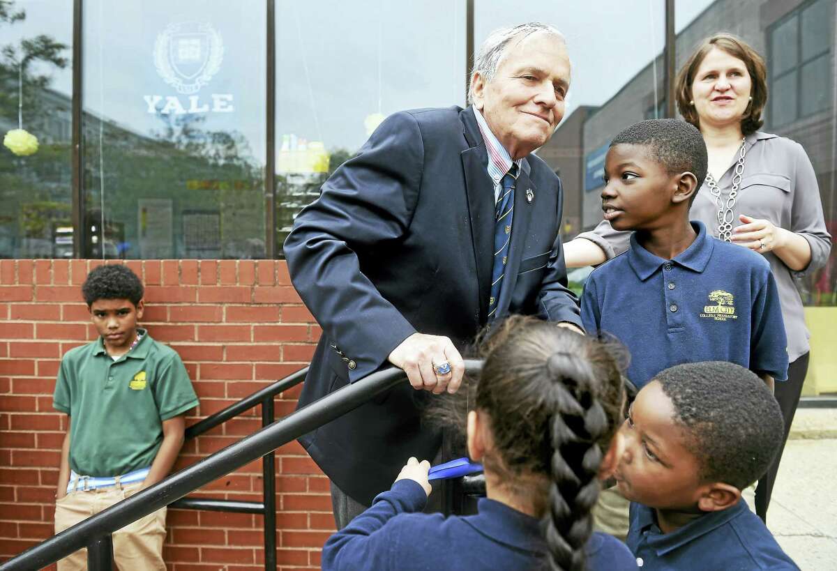 Joel E. Smilow, center, heads into the Elm City College Preparatory School, Joel Smilow Campus, after speaking with students in front of the school in New Haven Friday. At far right is Dacia Toll, co-CEO and president of Achievement First.