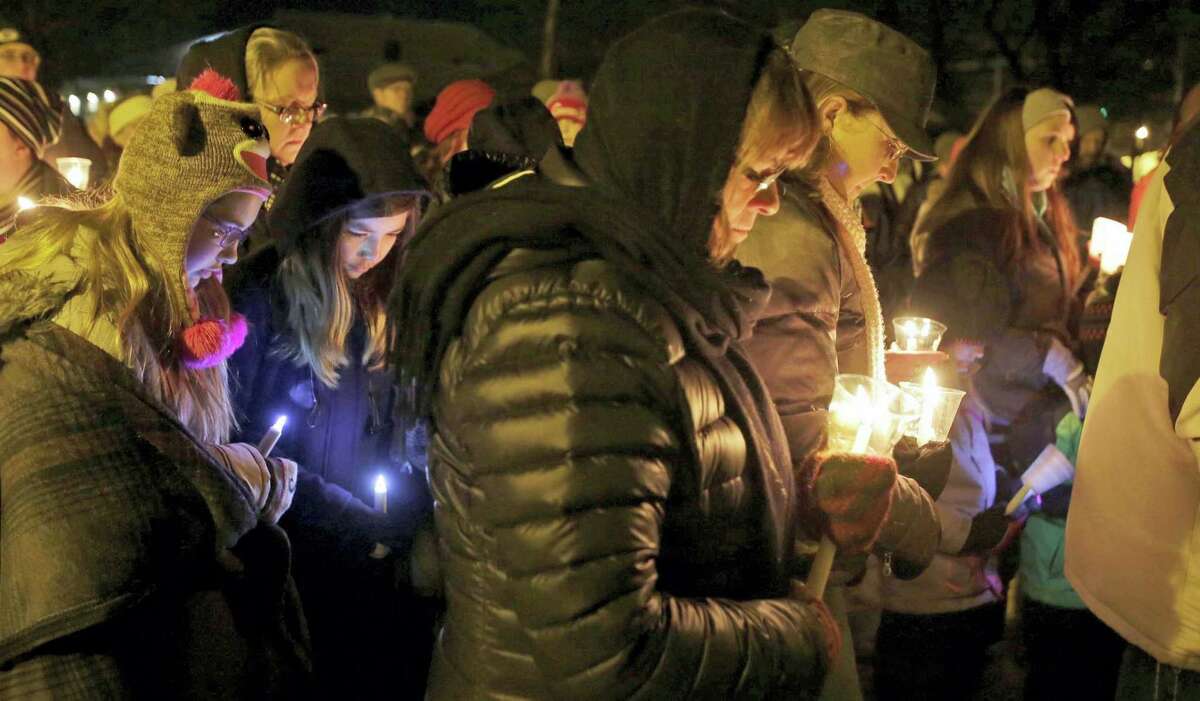 In this Jan. 29, 2016 photo, people hold candles in memory of the three deceased Sheboygan Falls children at River Park in Sheboygan Falls, Wis. Natalie Renee Martin, 11, Carter Maki, 7, and Benjamin Martin, 10, died in a house fire Jan. 26. Natalie, who died saving the lives of even younger children, is among 21 people being honored with Carnegie medals for heroism. The Carnegie Hero Fund Commission, based in Pittsburgh, announced the winners Tuesday, Dec. 20, 2016.