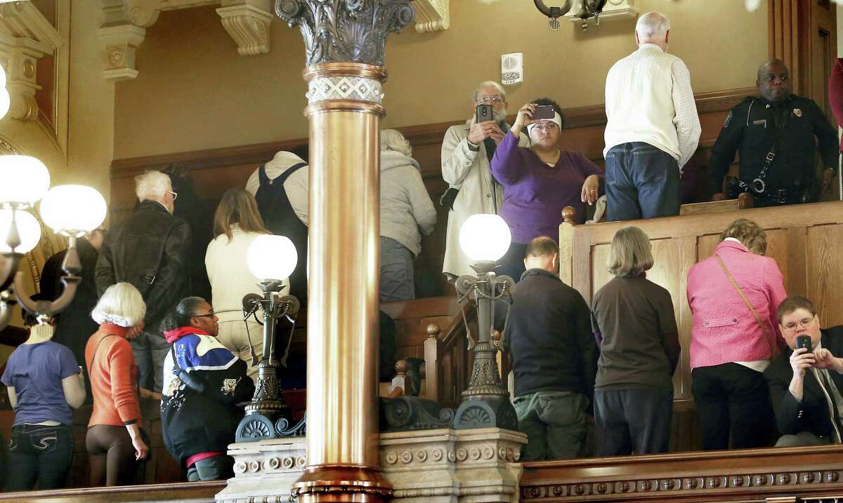 People turn their backs on Electoral College members Monday at the state Capitol as they vote in Topeka, Kan. Kansas’ six Republican members of the Electoral College have cast their ballots for President-elect Donald Trump, keeping with the state’s popular vote.