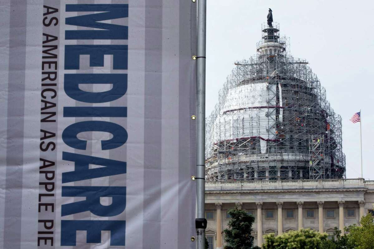 In this July 30, 2015 photo, a sign supporting Medicare is seen on Capitol Hill in Washington. A government report says Medicare beneficiaries can end up with higher hospital bills for some medical services as outpatients than as inpatients.