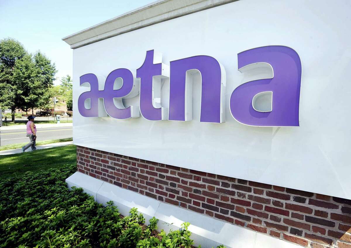 In this Tuesday, Aug. 19, 2014, file photo, a pedestrian walks past a sign for Aetna Inc., at the company headquarters in Hartford, Conn. Aetna reports financial results Thursday, Oct. 27, 2016.