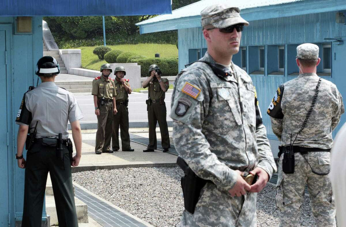 In this July 27, 2014, file photo, North Korean army soldiers watch the south side while a South Korean and United States Army soldiers stand guard at the border villages of Panmunjom in Paju, South Korea. North Korea has threatened on Saturday, Aug. 27, 2016, to aim fire at the lighting equipment used by American and South Korean troops at a truce village inside the Demilitarized Zone that divides the two Korea.