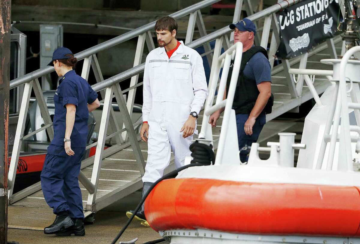 Nathan Carman, center, disembarks from a small boat at the US Coast Guard station in Boston, Tuesday. Carman spent a week at sea in a life raft before being rescued by a passing freighter.