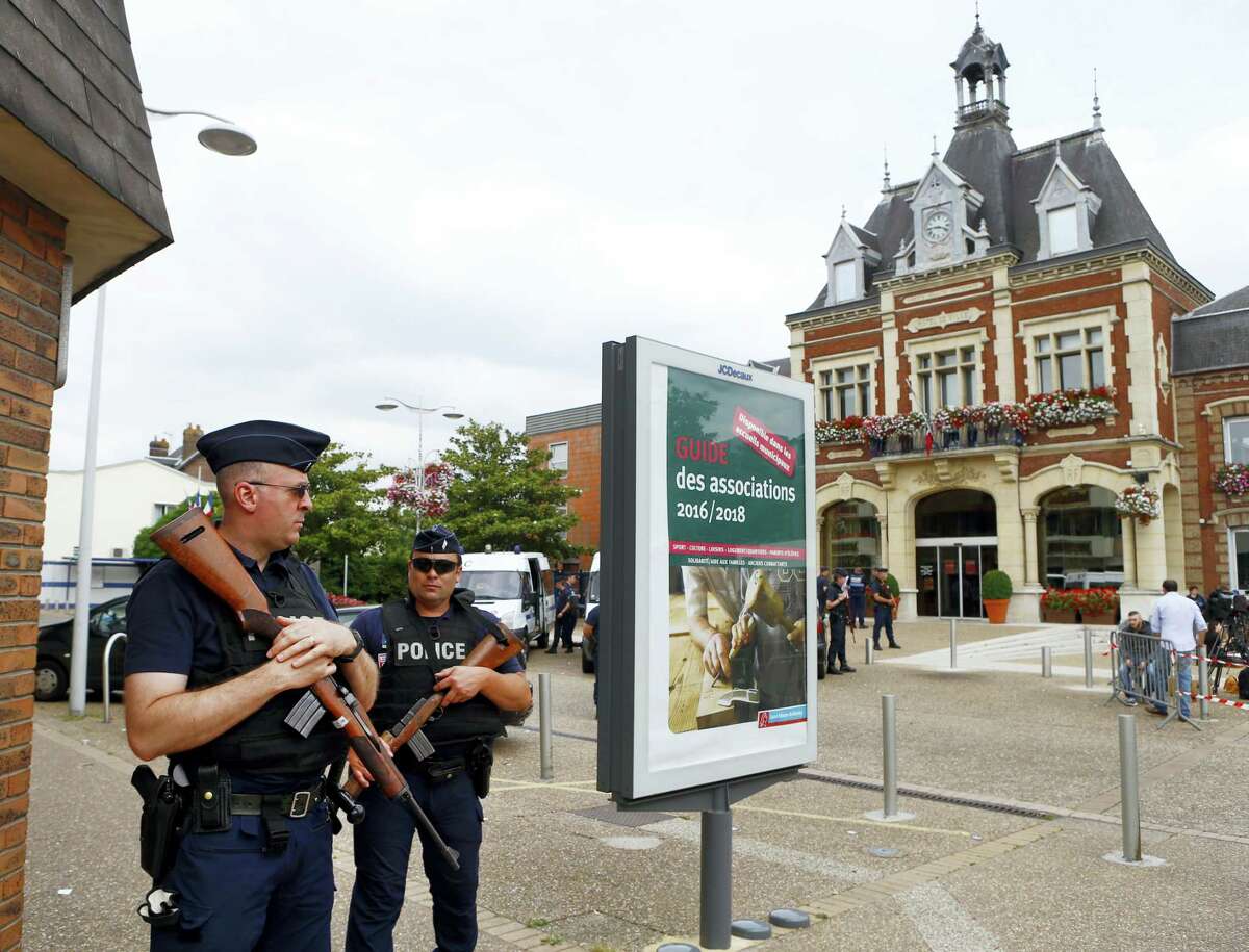 French police officers stand guard in front of the Saint-Etienne-du-Rouvray’s city hall, Normandy, France, after an attack on a church that left a priest dead, Tuesday, July 26, 2016. Two attackers invaded a church Tuesday during morning Mass near the Normandy city of Rouen, killing an 84-year-old priest by slitting his throat and taking hostages before being shot and killed by police, French officials said.