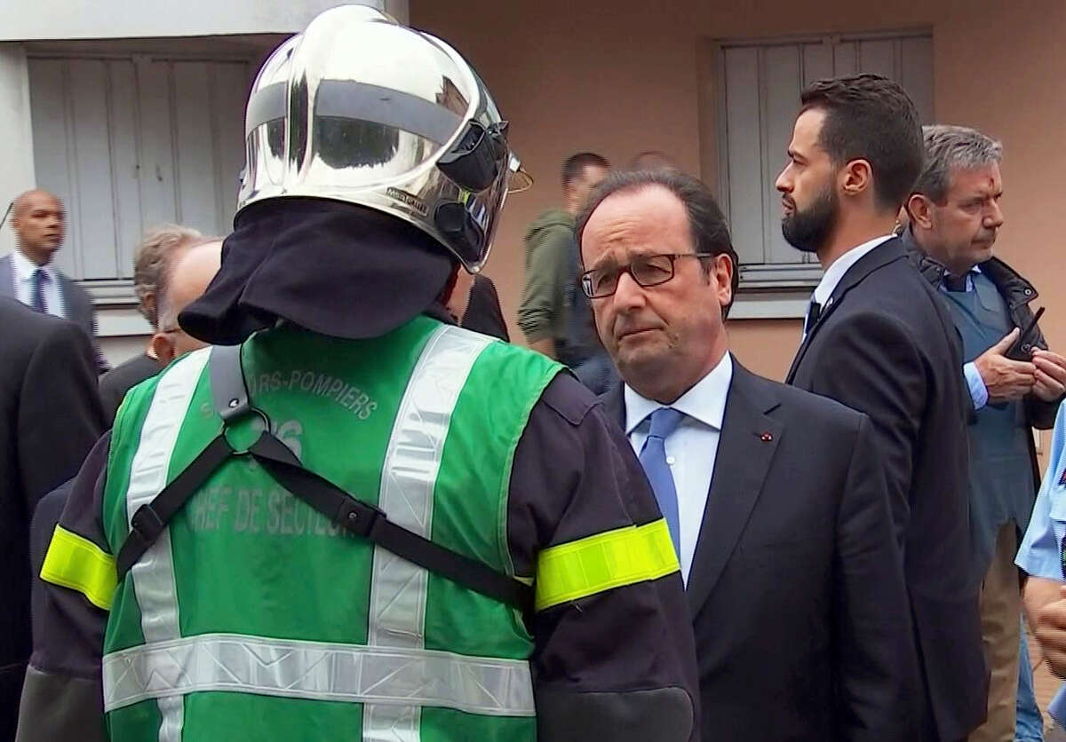 In this grab made from video, French President Francois Hollande speaks with emergency services personnel after arriving at the scene of the hostage situation in Normandy, France, Tuesday, July 26, 2016. Two attackers took hostages inside a French church during morning Mass on Tuesday in the Normandy town of Saint-Etienne-du-Rouvray, killing an 86-year-old priest by slitting his throat before being shot and killed by police, French officials said. The Islamic State group claimed responsibility for the attack.