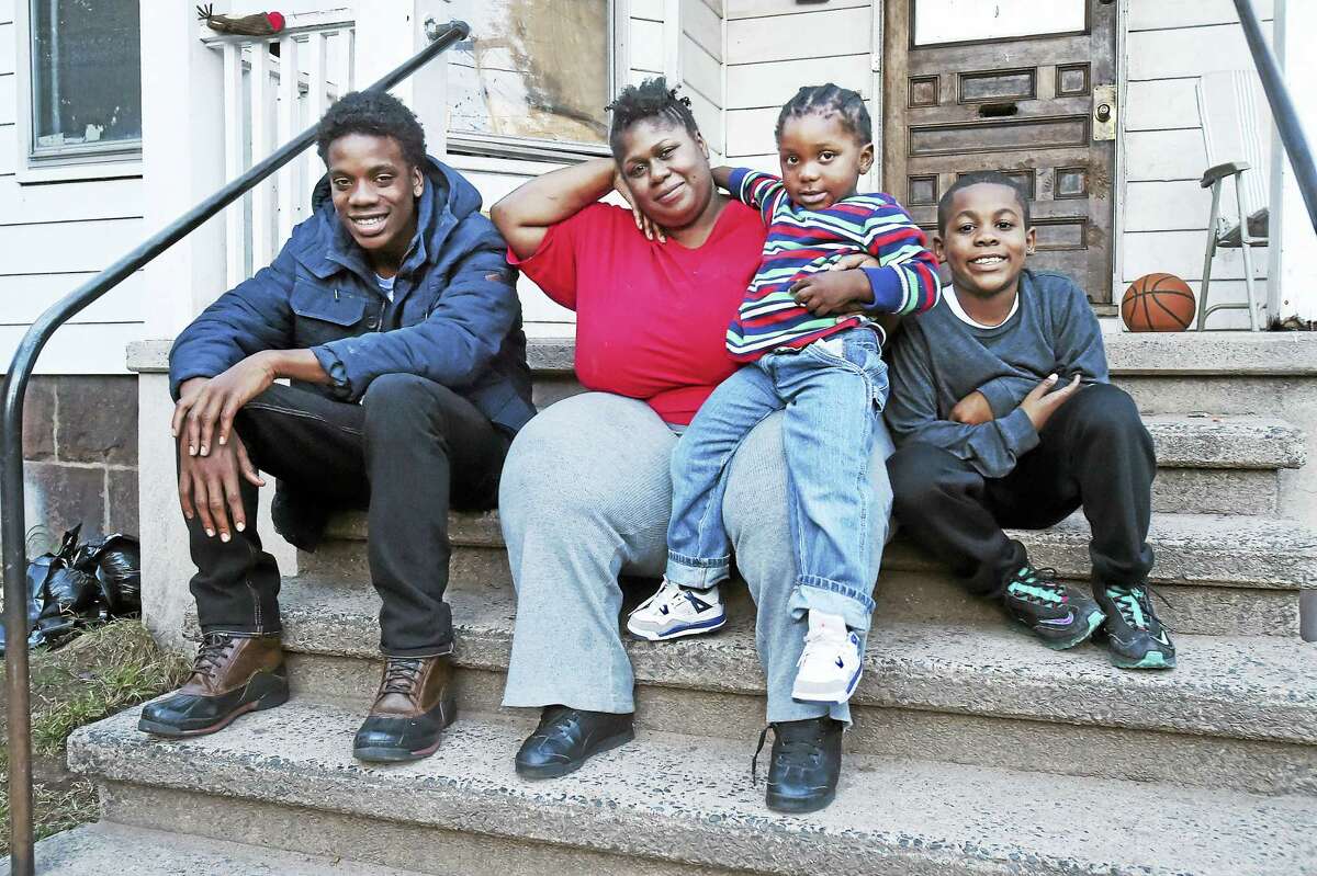 Latasha O’Bryan and three of her four sons, Ja-Sen Smith, 16, Jamyl Mercer, 3, and Isaiah Staton, 9, on the front porch of her parents’ New Haven home Wednesday. O’Bryan’s son Kenneth Watts, also 16, is not pictured.