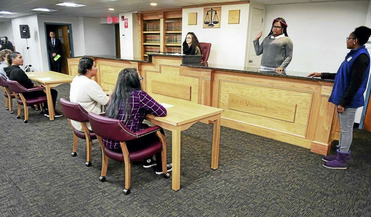 Mock juror Ruby Jones, a High School in the Community Academy for Law and Social Justice student, second from right, is sworn in by classmate and mock bailiff Di’Jhon McCoy, right, at the school’s new courtroom classroom Wednesday.