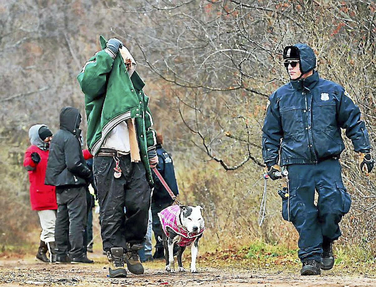 A homeless man with his dog, New Haven Police and city officials leave a New Haven homeless encampment off of I-91 exit 6, near the Mill River before it was razed Thursday. Residents of the camp were ordered by the City of New Haven last week to leave the encampment.