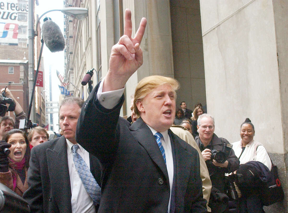 In this March 18, 2004 photo, developer Donald Trump signals to those waiting in line at a casting call for the second season of his television show, “The Apprentice,” in New York.