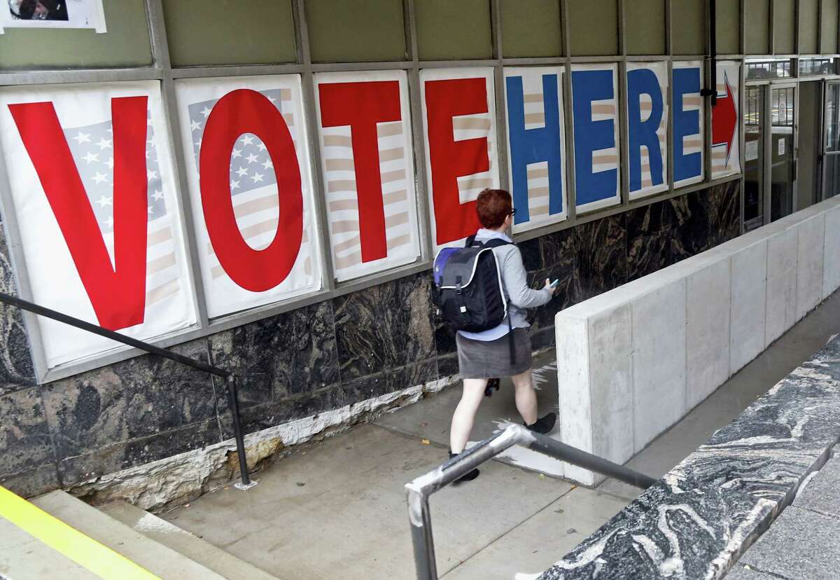 A woman passes a large sign as she arrives to vote Friday in Minneapolis. Election Day is more than a month away, but the voting was already underway Friday, as Minnesota kicked off its first presidential cycle where all voters across the state can cast their ballots early.