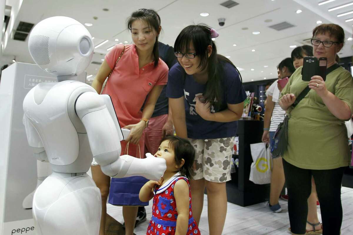 Shoppers talk to SoftBank Corp.’s companion robot Pepper at a store in Tokyo recently. Pepper robots, equipped with a “heart” designed to not only recognize human emotions but react with simulations of anger, joy and irritation, are on sale.