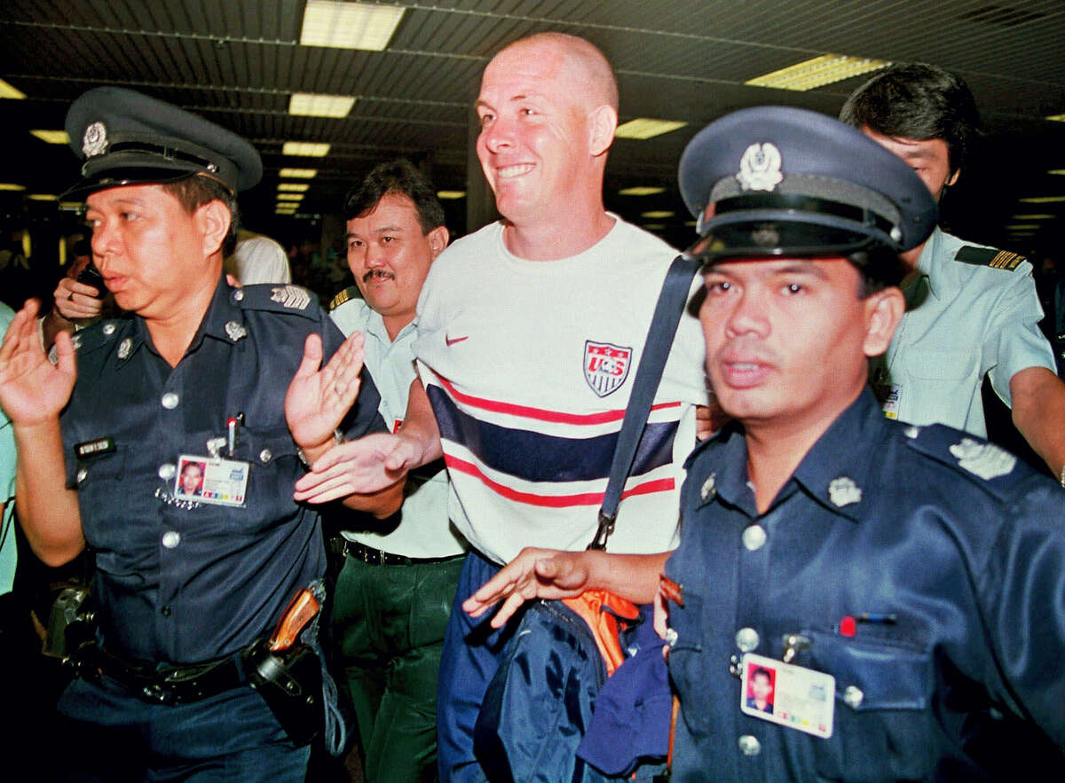 Former Barings bank trader Nick Leeson, center, is led through immigration by Singapore police officials at Changi airport shortly after he was freed from prison in Singapore. The British trader, who caused the collapse of Barings Bank in 1995 when he lost more than $1 billion in unauthorized trades, was released from a Singapore jail after serving 3½ years.