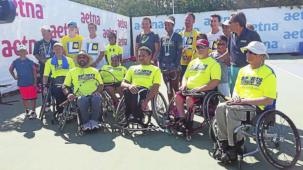 David Kelly, middle row left, Carlos Quiles, front row middle, and other members of the Gaylord Hospital Sports Association pose with women tennis players Raquel Atawo and Abigail Spears.