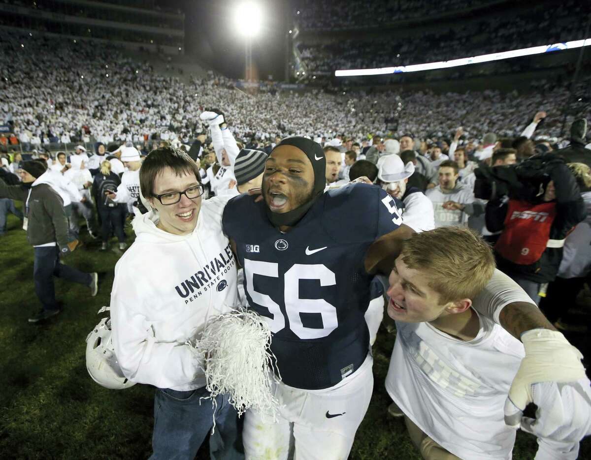Penn State’s Tyrell Chavis (56) celebrates with fans as they rush the field after Penn State upset Ohio State on Saturday.