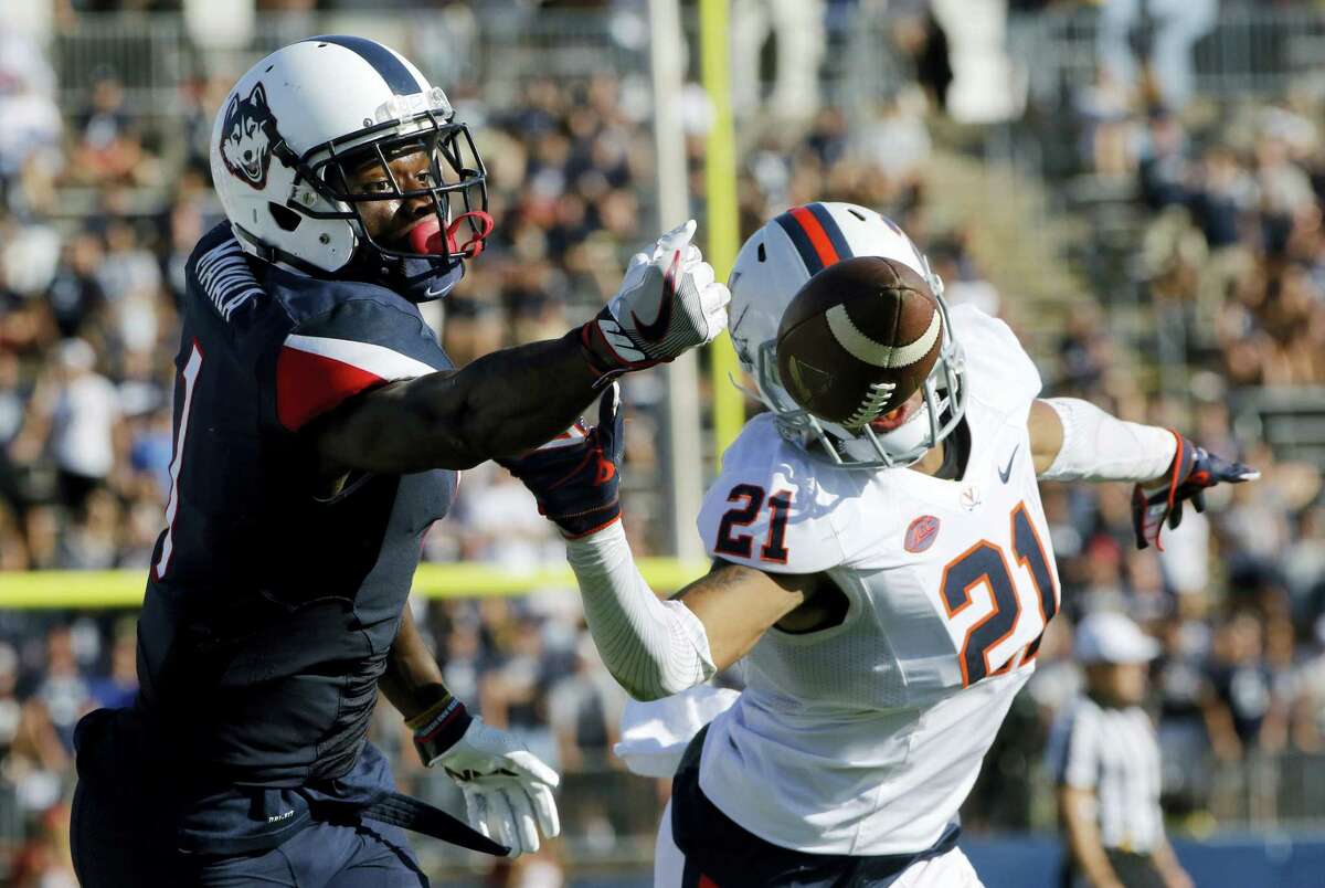 Connecticut’s Hergy Mayala, left, and Virginia’s Juan Thornhill reach for an incomplete pass during Saturday’s game.